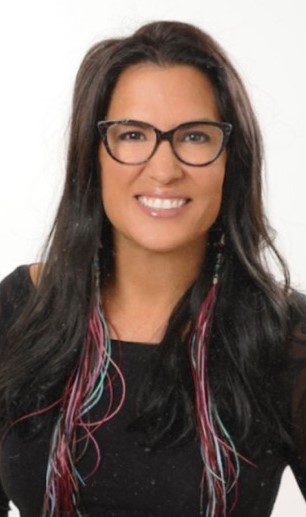 A woman in glasses is smiling for the camera.