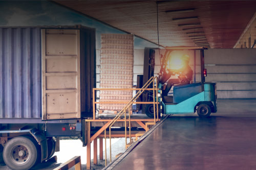 A forklift truck is loading a container in a warehouse.