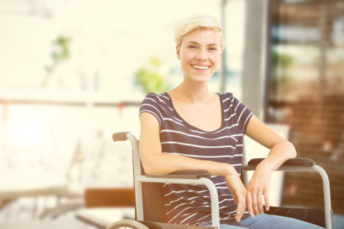 A woman is sitting in a wheelchair and smiling.