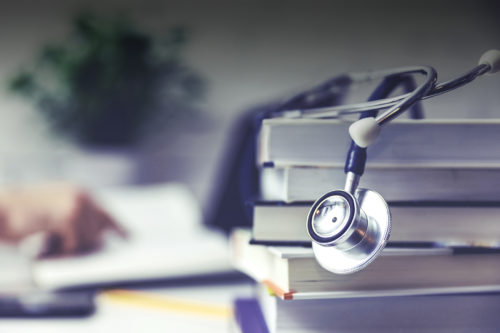 A stethoscope sits on top of a stack of books.