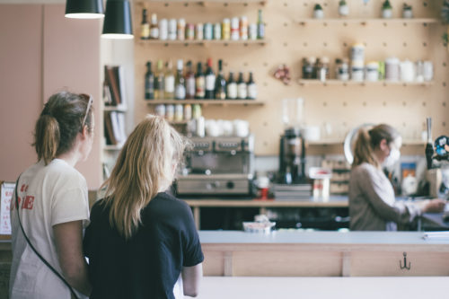 Two women standing at the counter of a coffee shop.