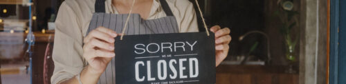 A woman holding up a sign that says sorry we are closed.