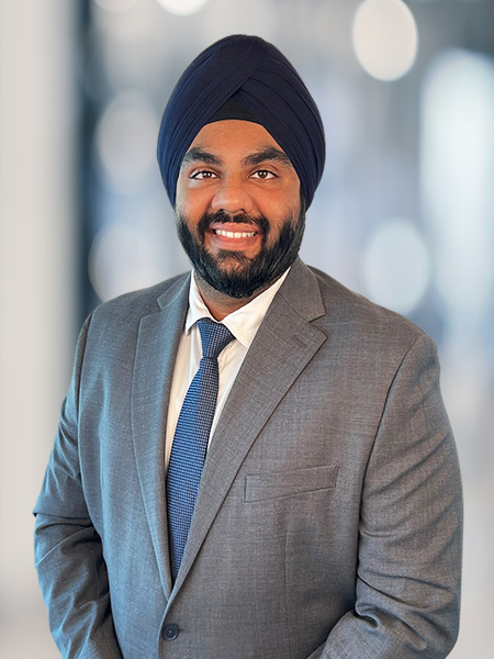 A man in a suit and turban smiling.