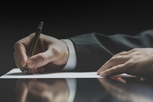 A businessman signing a document with a pen.