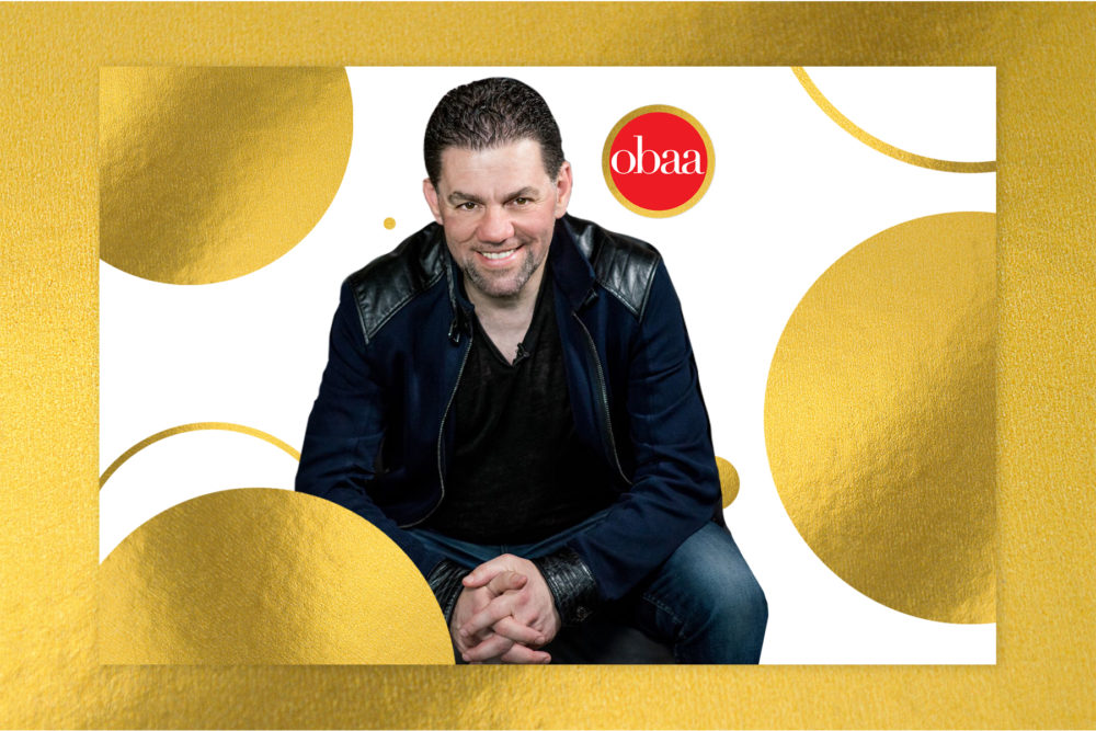 A man is sitting on a gold background.