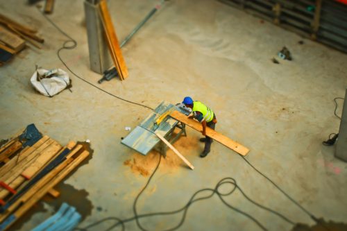 An aerial view of a construction worker working on a piece of wood.