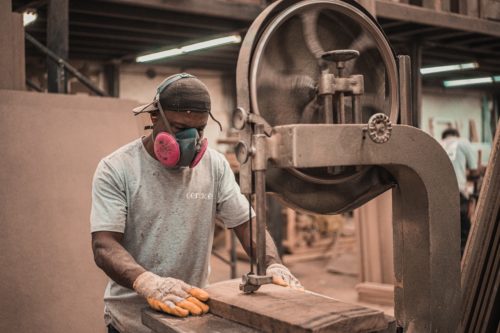 A man wearing a mask is working on a machine.