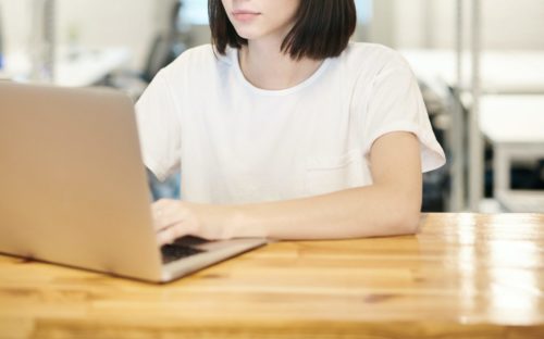 A young woman sitting at a desk using a laptop.