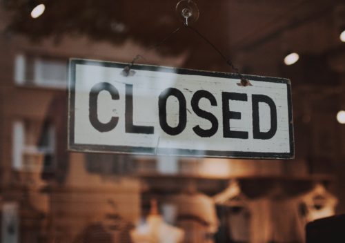 A closed sign hanging from the window of a store.