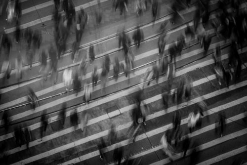 Black and white image of blurry pedestrians crossing the roaf