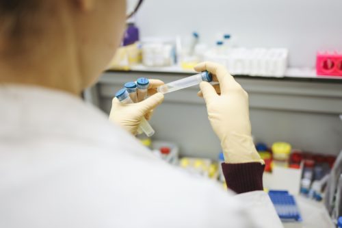 A woman is holding a test tube in a lab.