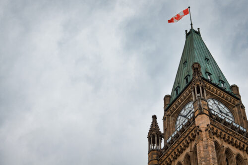 A clock tower with a canadian flag on it.